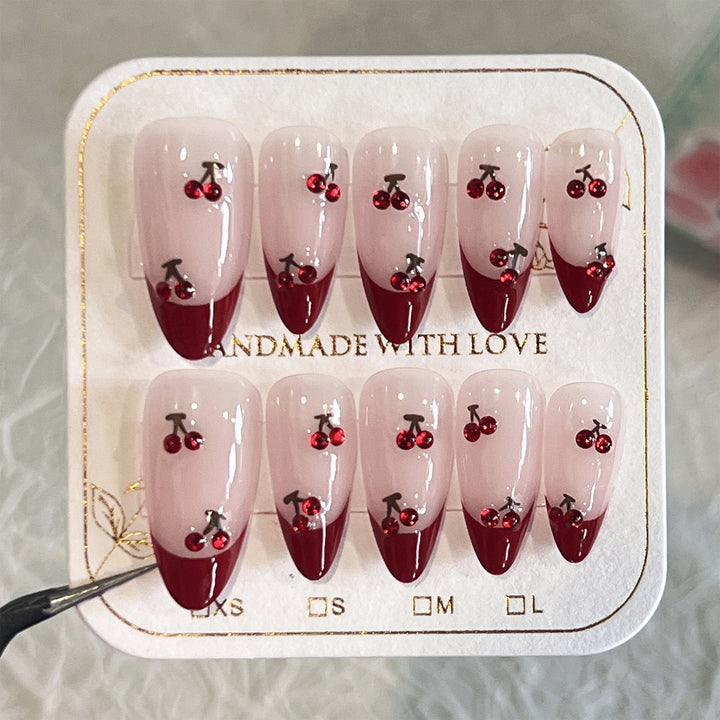 Artful stiletto nails with cherry motifs and glitter accents Bowlift