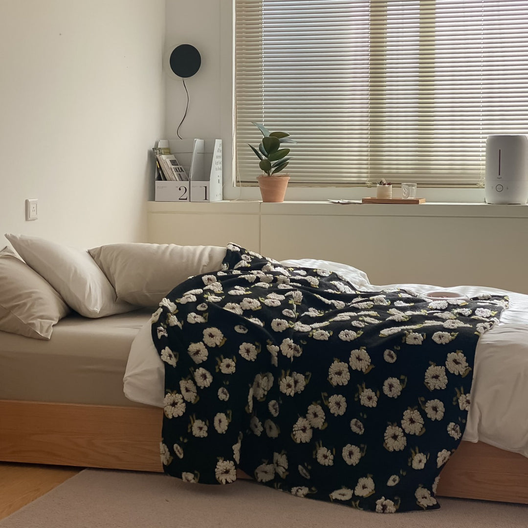 Patterned throw blanket with woven flower appliqués