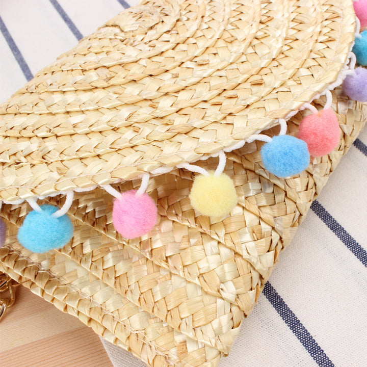 Clutch made of handwoven natural material with decorative pompons Bowlift
