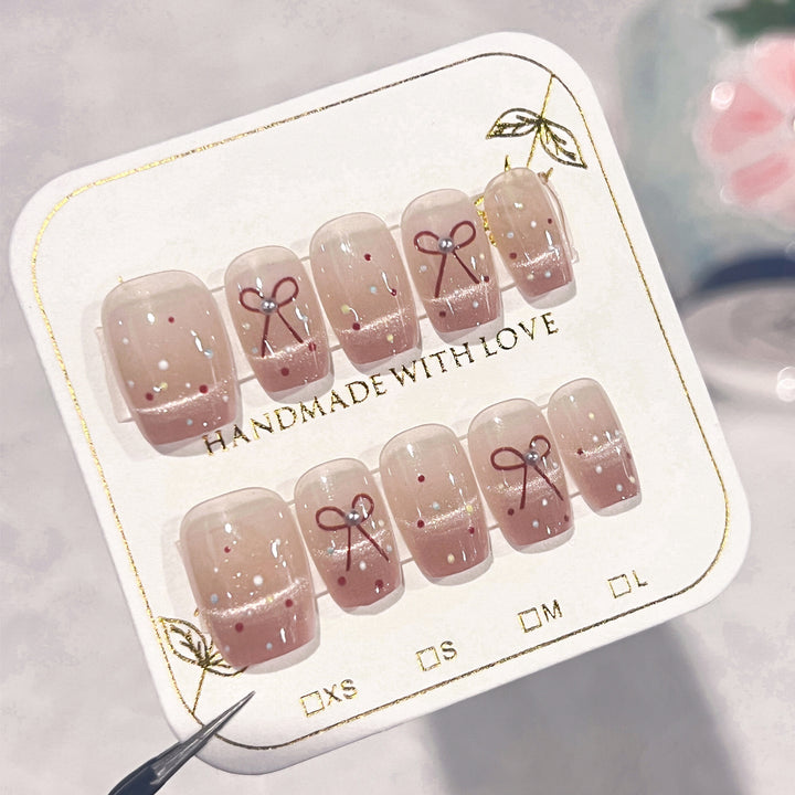 Artificial nail art with elegant bows and glitter accents Bowlift