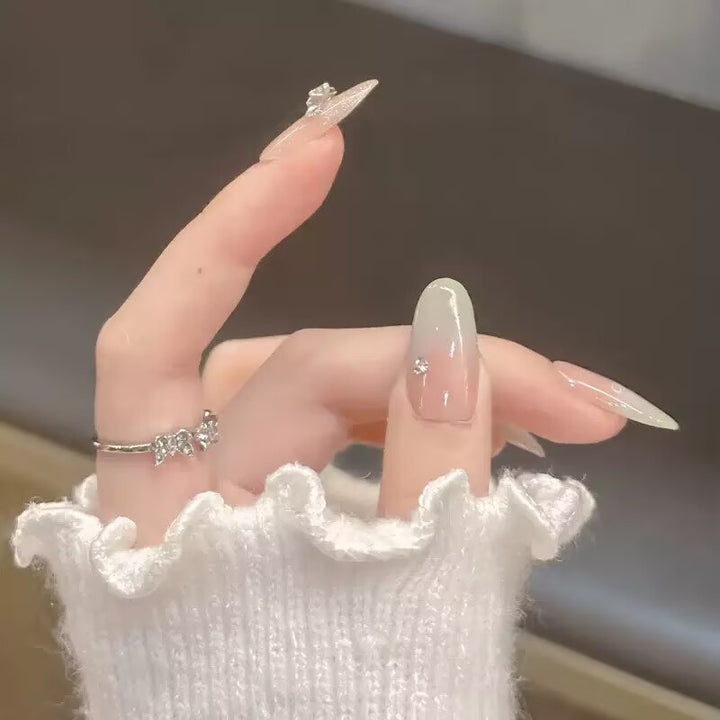 Artificial nails with delicate ombre design and intricate embellishments