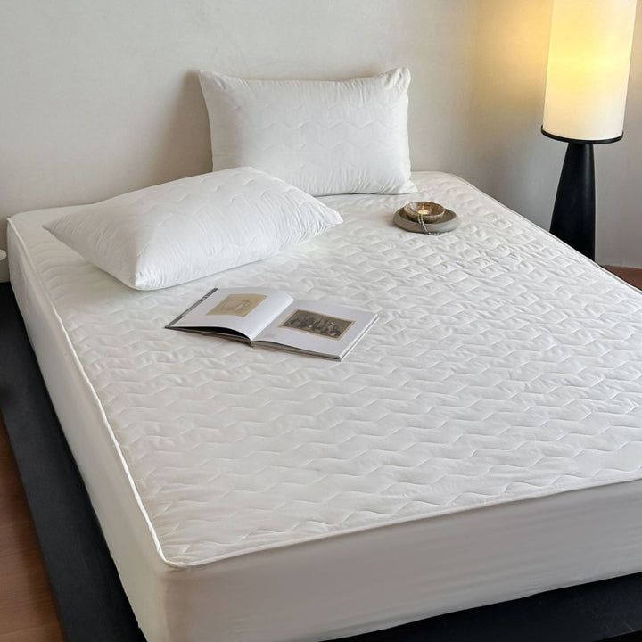 Padded mattress protector with all-round stretch and quilting